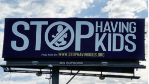 Large roadside billboard displaying the message ‘Stop Having Kids’ with a no-baby symbol.