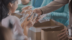 Hands exchanging packaged food over a table at a community food distribution, symbolizing support for food-insecure families.